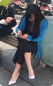 坐在广场边长椅上玩手机的蓝衣女郎，象牙色细跟白高典雅漂亮