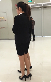 大型卖场围观产品推介活动的两个制服高跟女郎