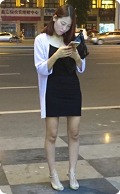 夜幕下站在广场边玩手机的少妇，身材打扮腿型都不错