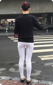 街边穿着白色紧身裤打电话的女郎